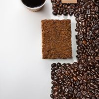 عکس گرافیکی تبلیغاتی برای قهوه میلو شامل دانه قهوه و یک قهوه