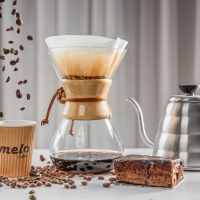 عکس گرافیکی تبلیغاتی برای قهوه میلو شامل دانه قهوه و یک قهوه و قهوه ساز
